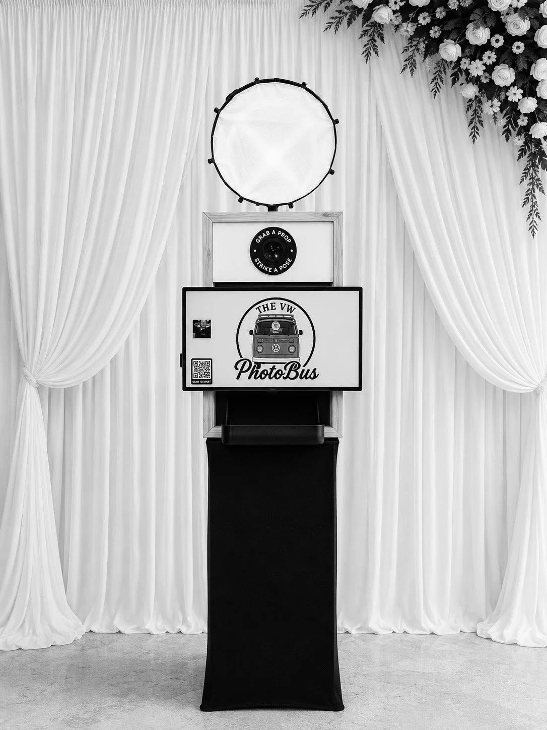 Elegant freestanding photo booth with white curtain backdrop and prop table