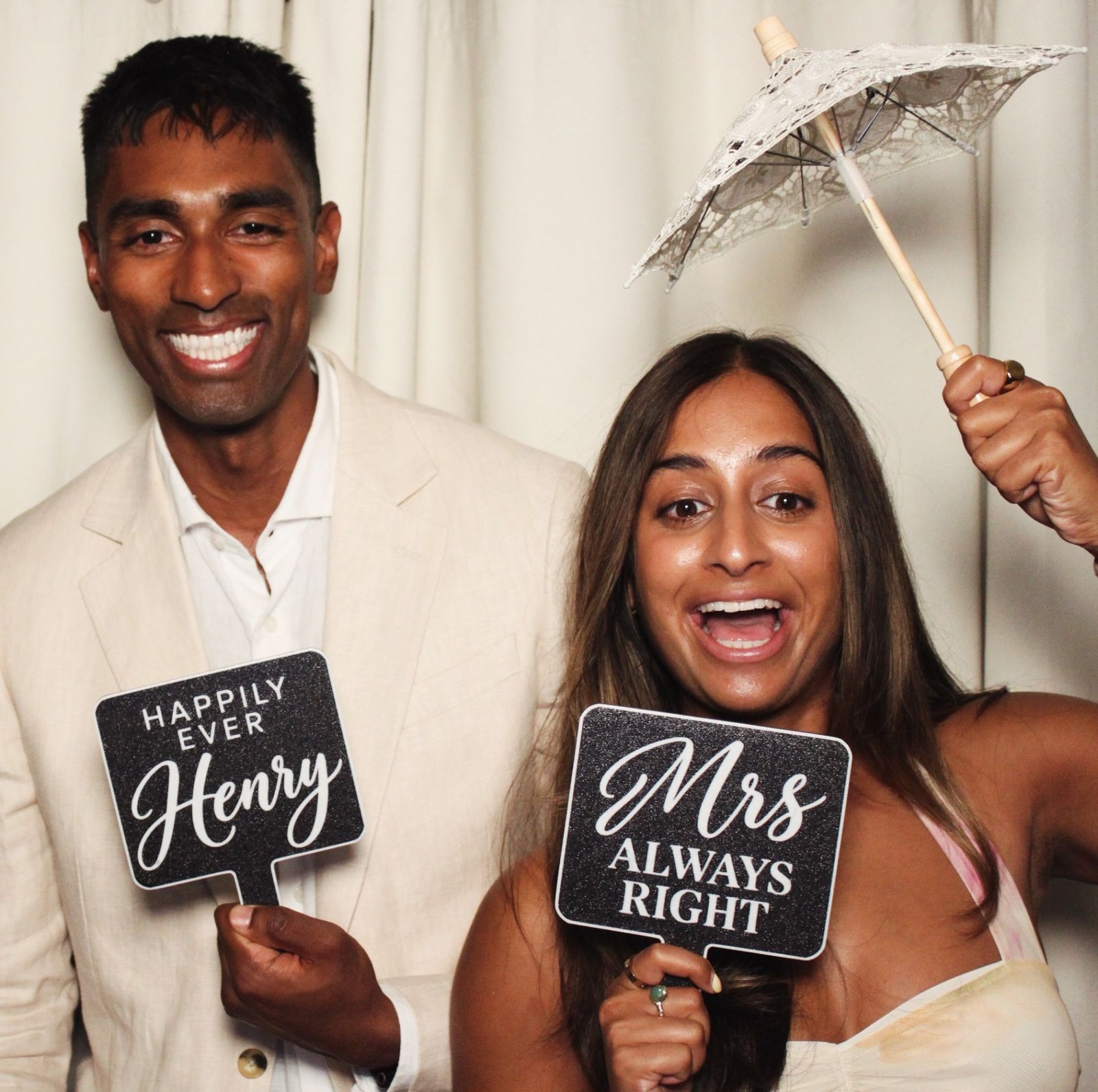 A couple holding fun signs reading Happily Ever After and Mrs Always Right at the photo booth