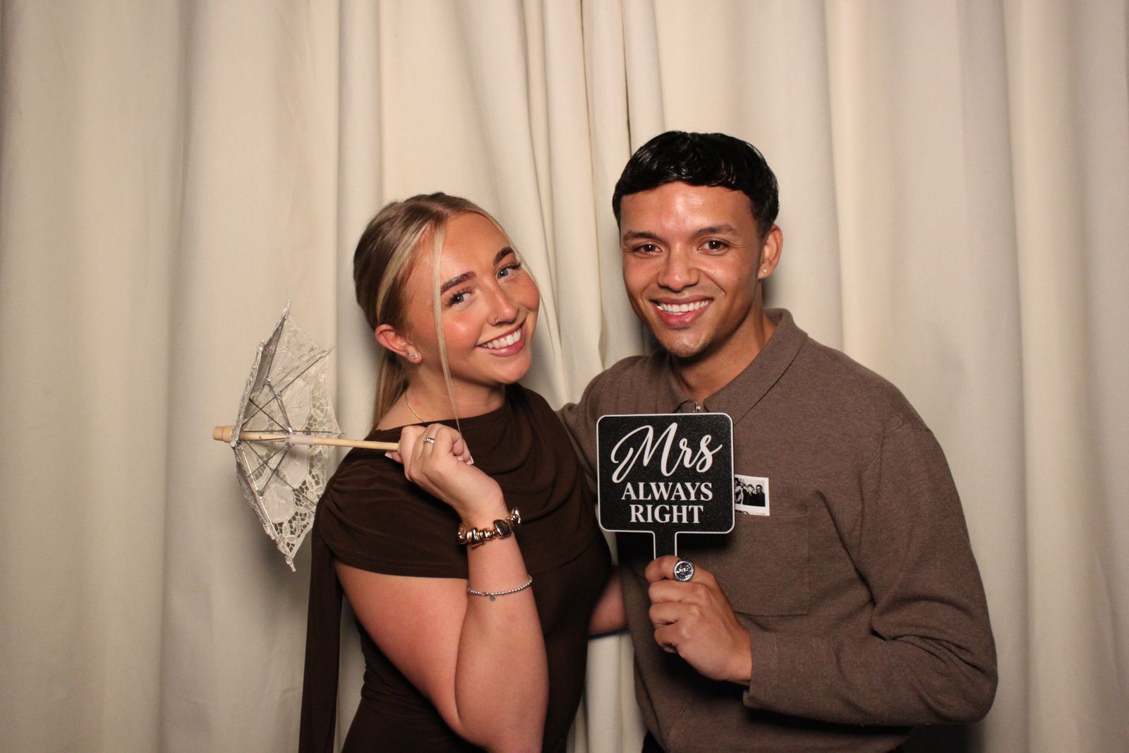 A couple at the photo booth, one holding a lace parasol and the other a Mrs Always Right sign