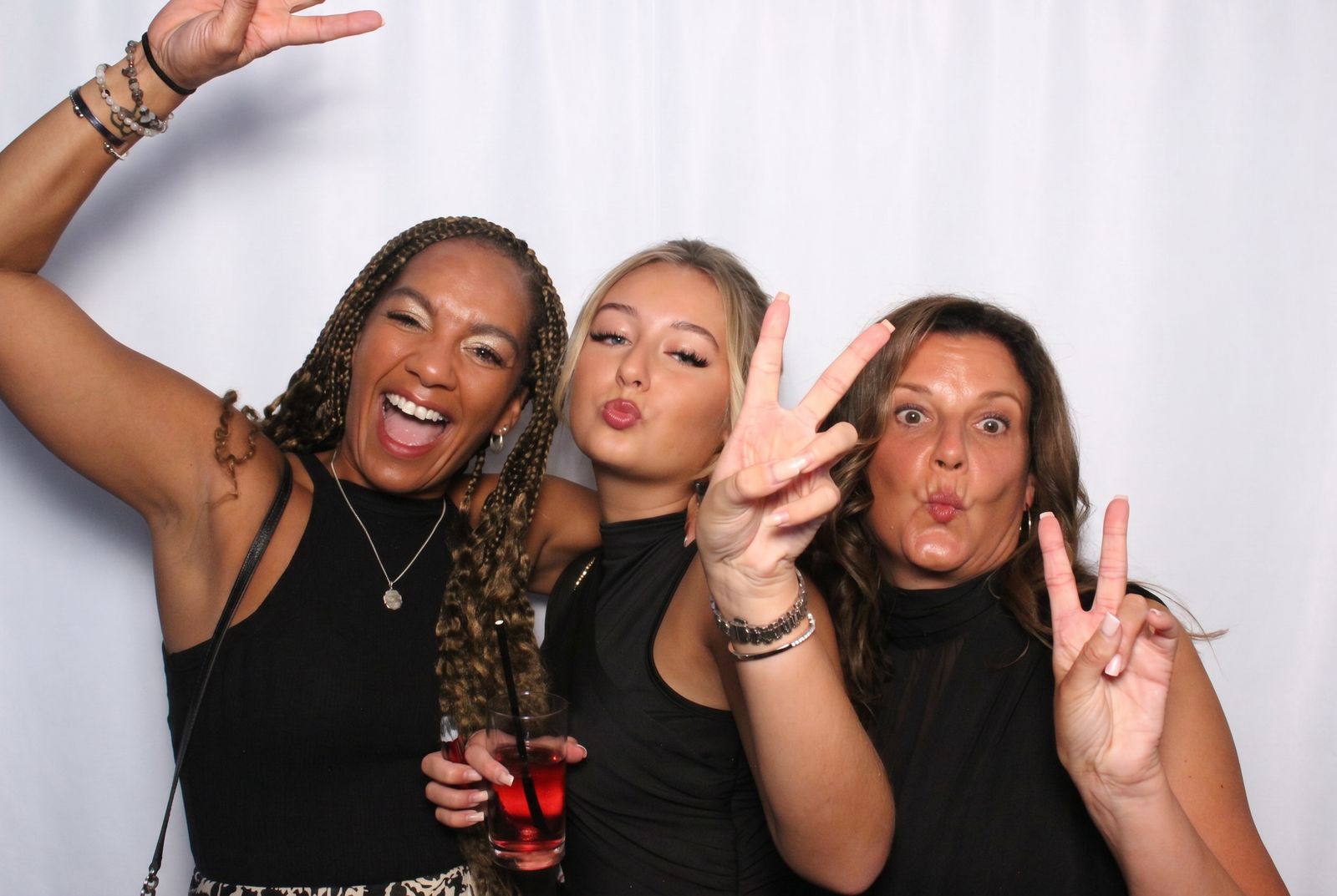 Three guests posing with peace signs and big smiles inside the booth