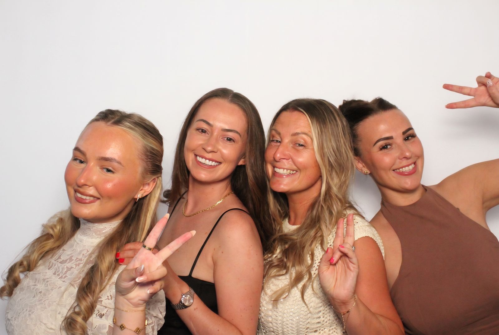 Group of four guests posing with peace signs in the photo booth