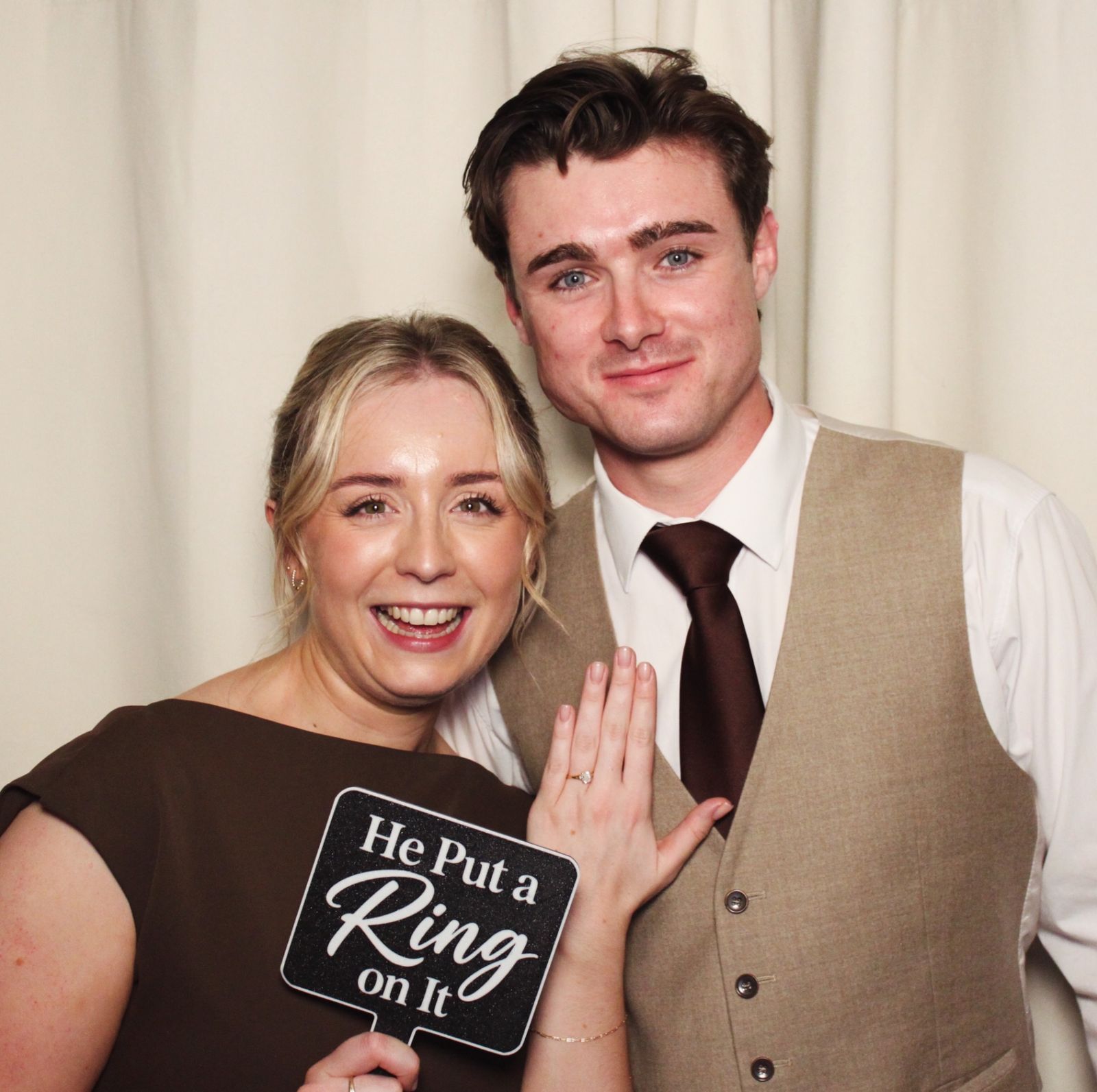 A woman holding a He Put a Ring on It sign next to a man at the photo booth