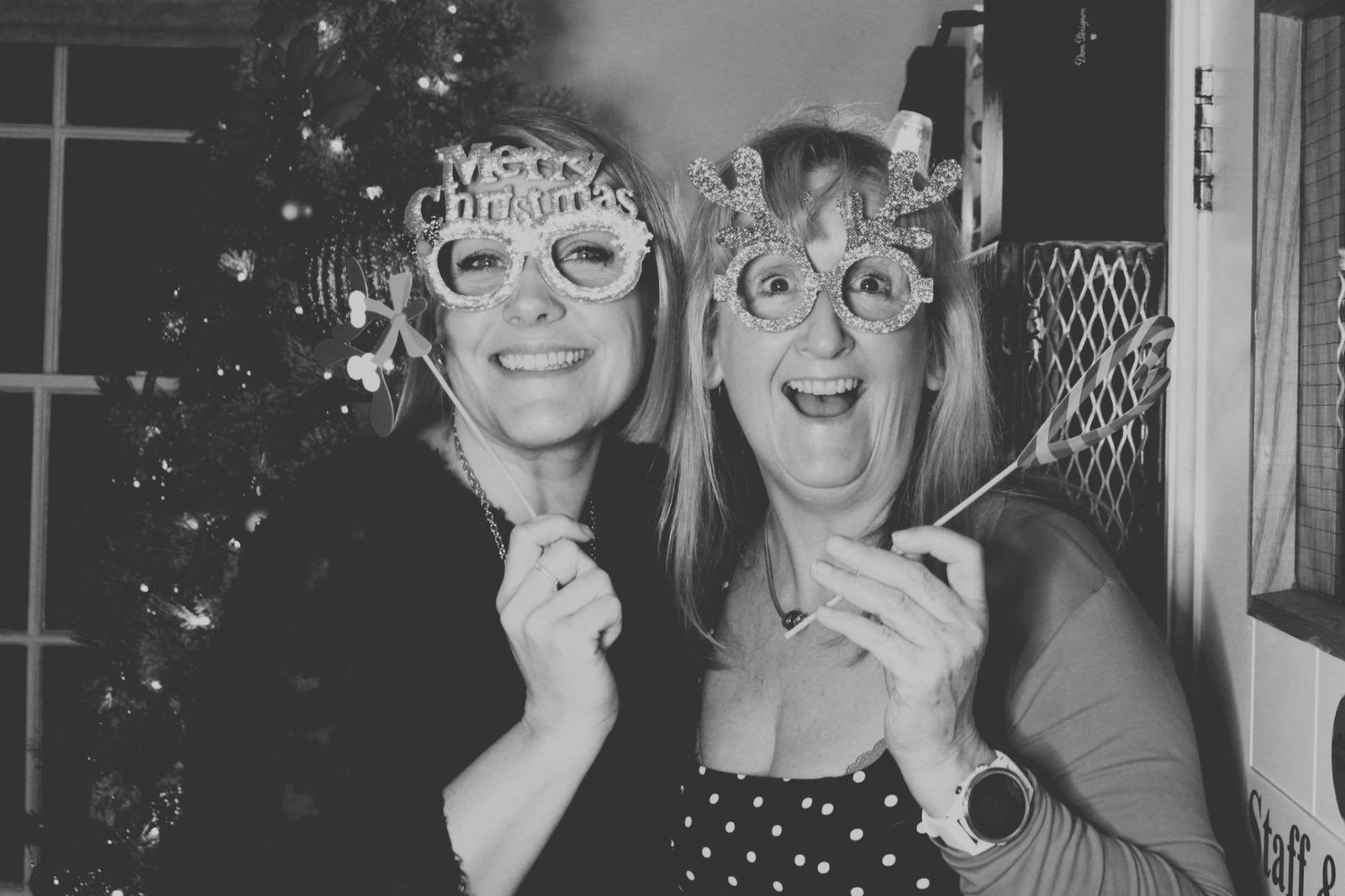 Two guests wearing festive Merry Christmas and reindeer glasses props