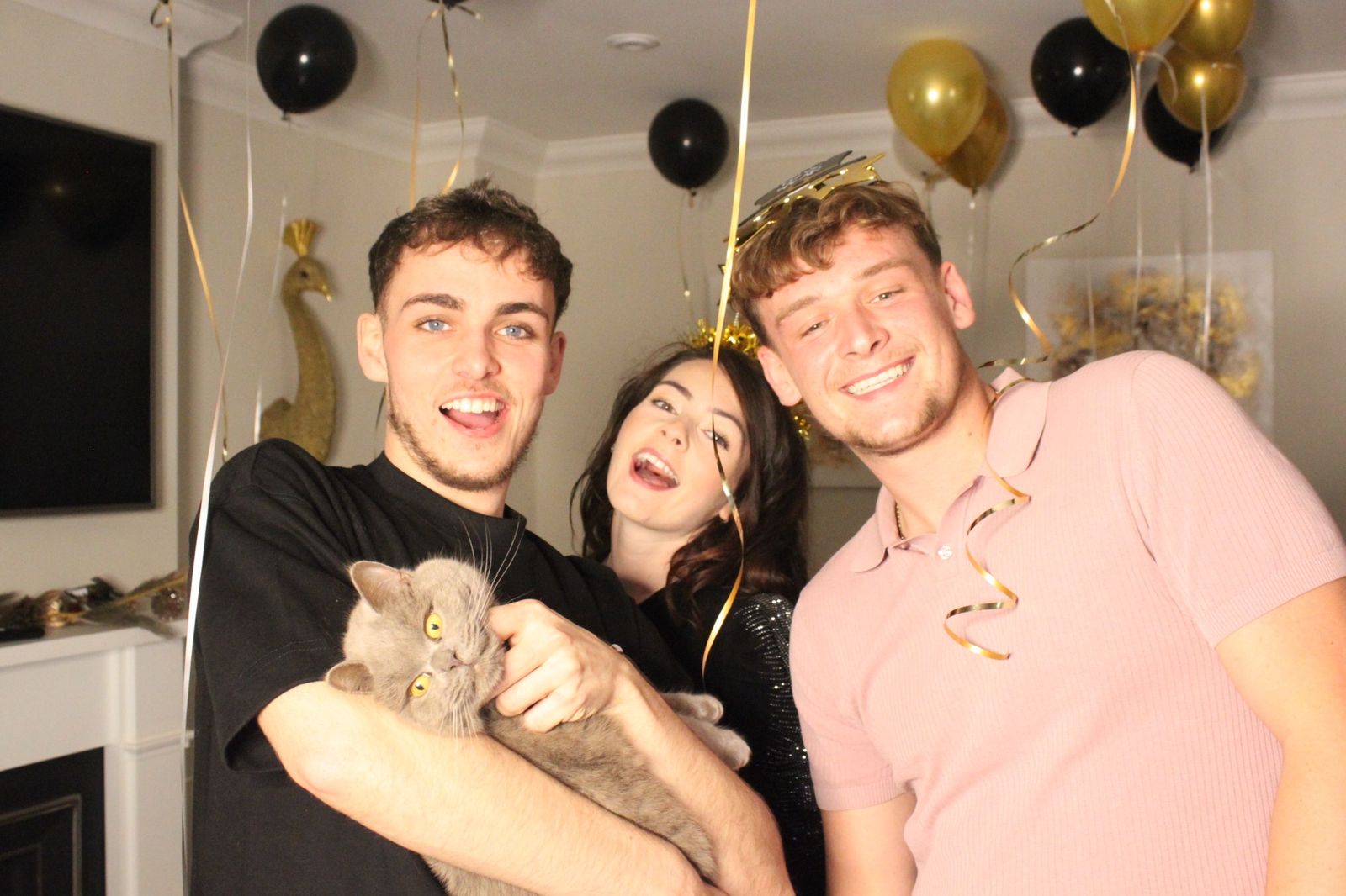Two guests and a friend holding a cat at a New Year's Eve party