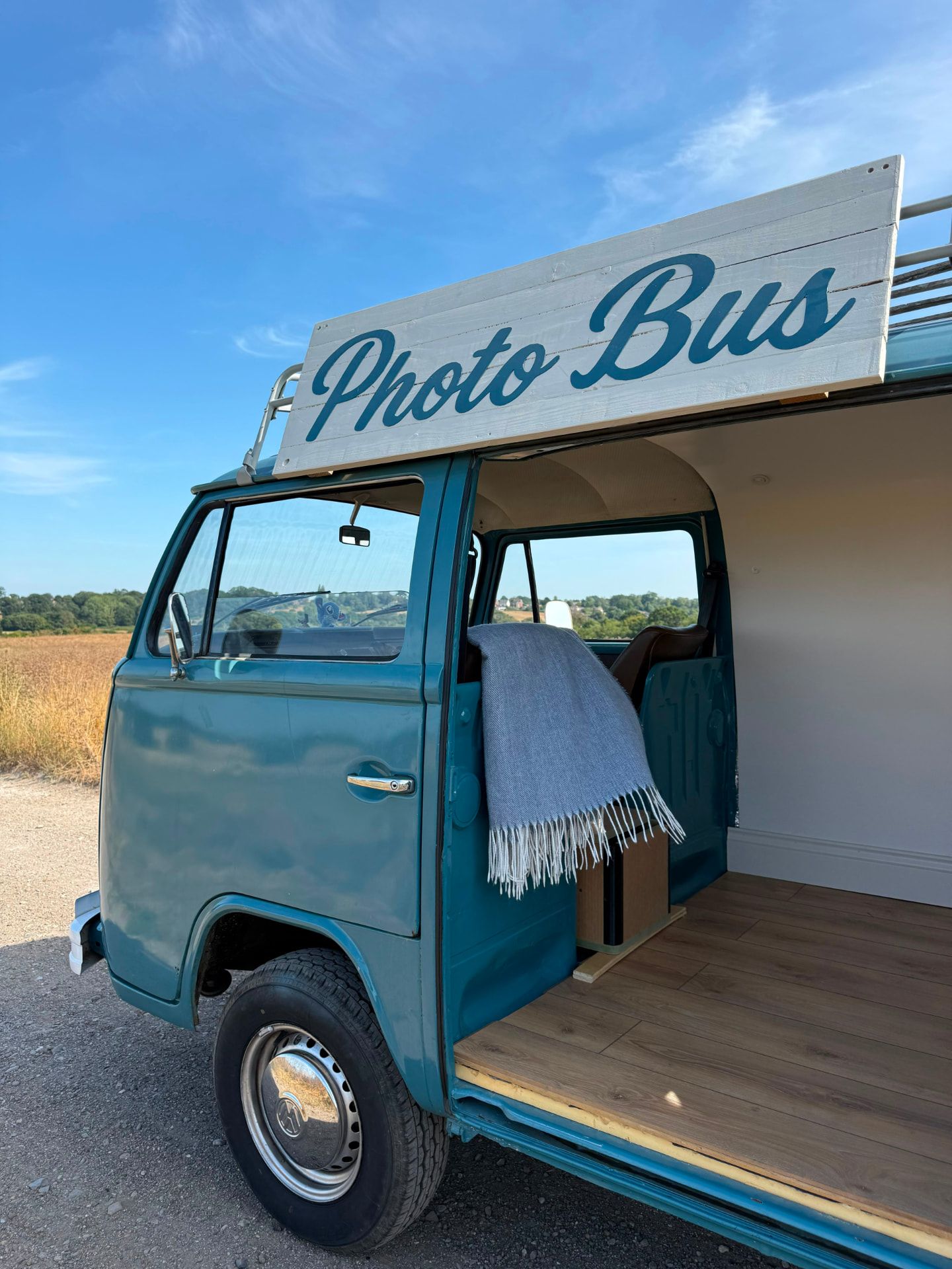 Stitch the VW Photo Bus with her hand-painted sign against a summer sky