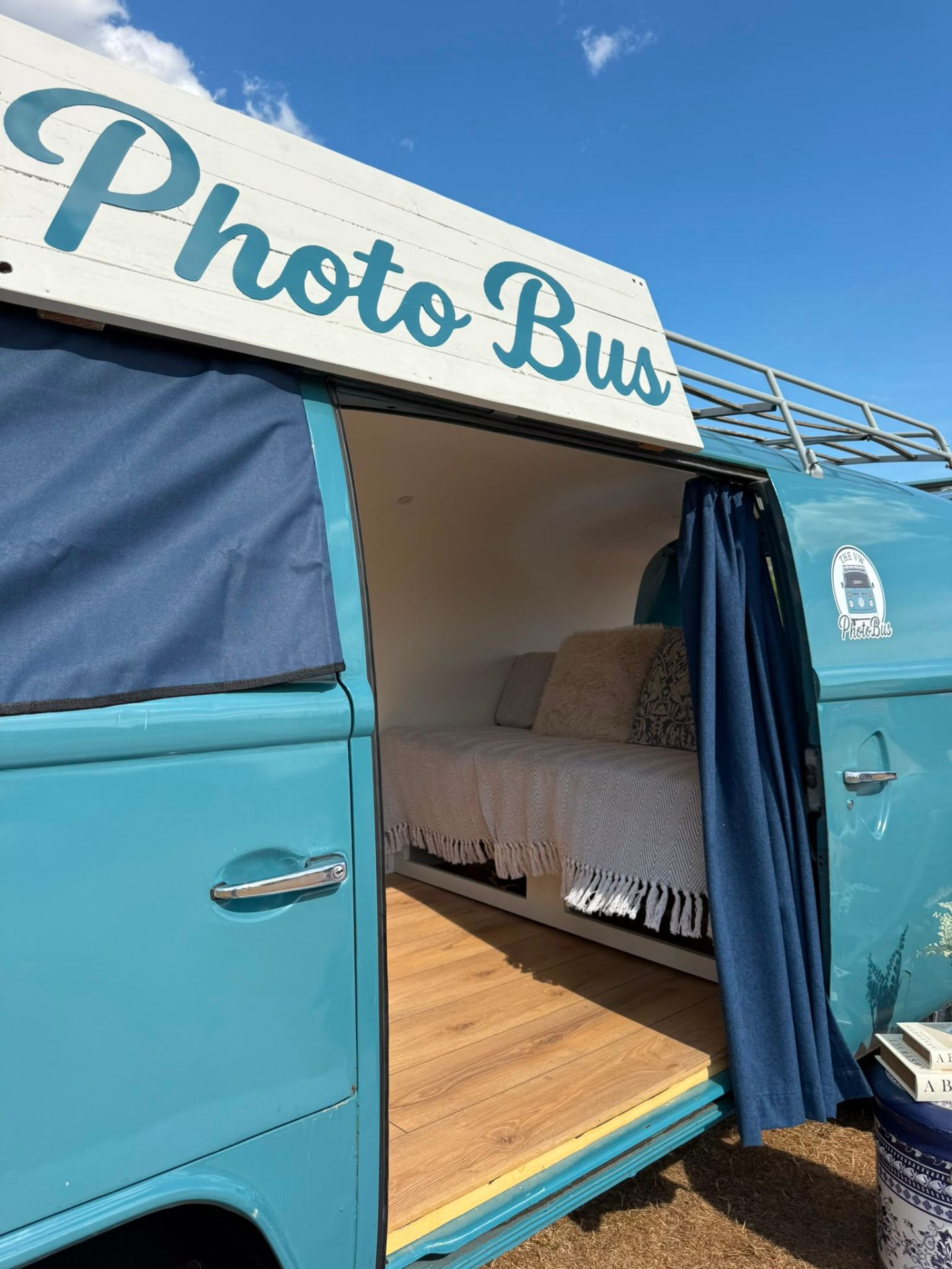 The Photo Bus sign above the open side door showing the styled interior bench inside the VW camper